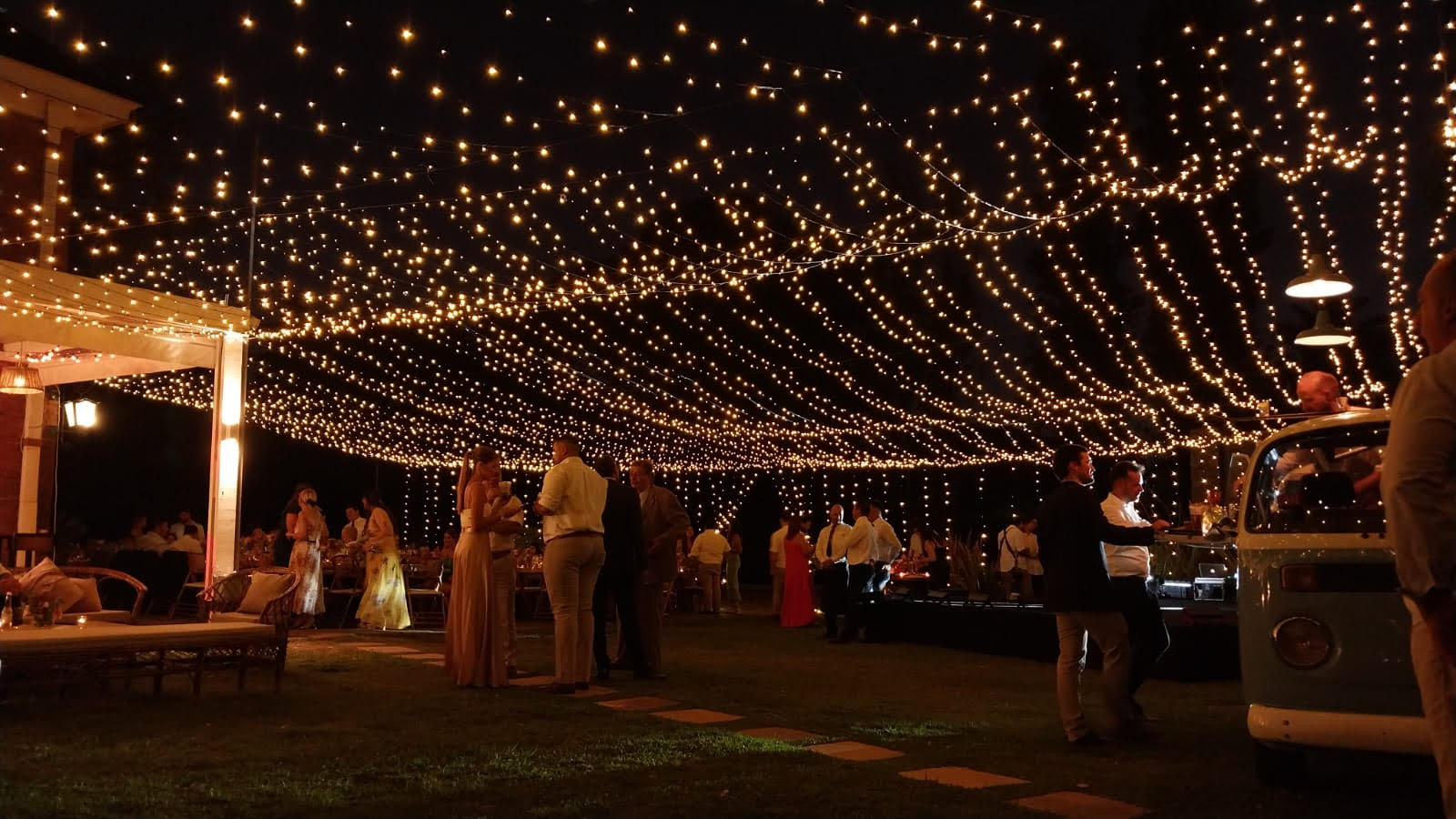 Techo de luces cálidas cubriendo recepción al aire libre, invitados