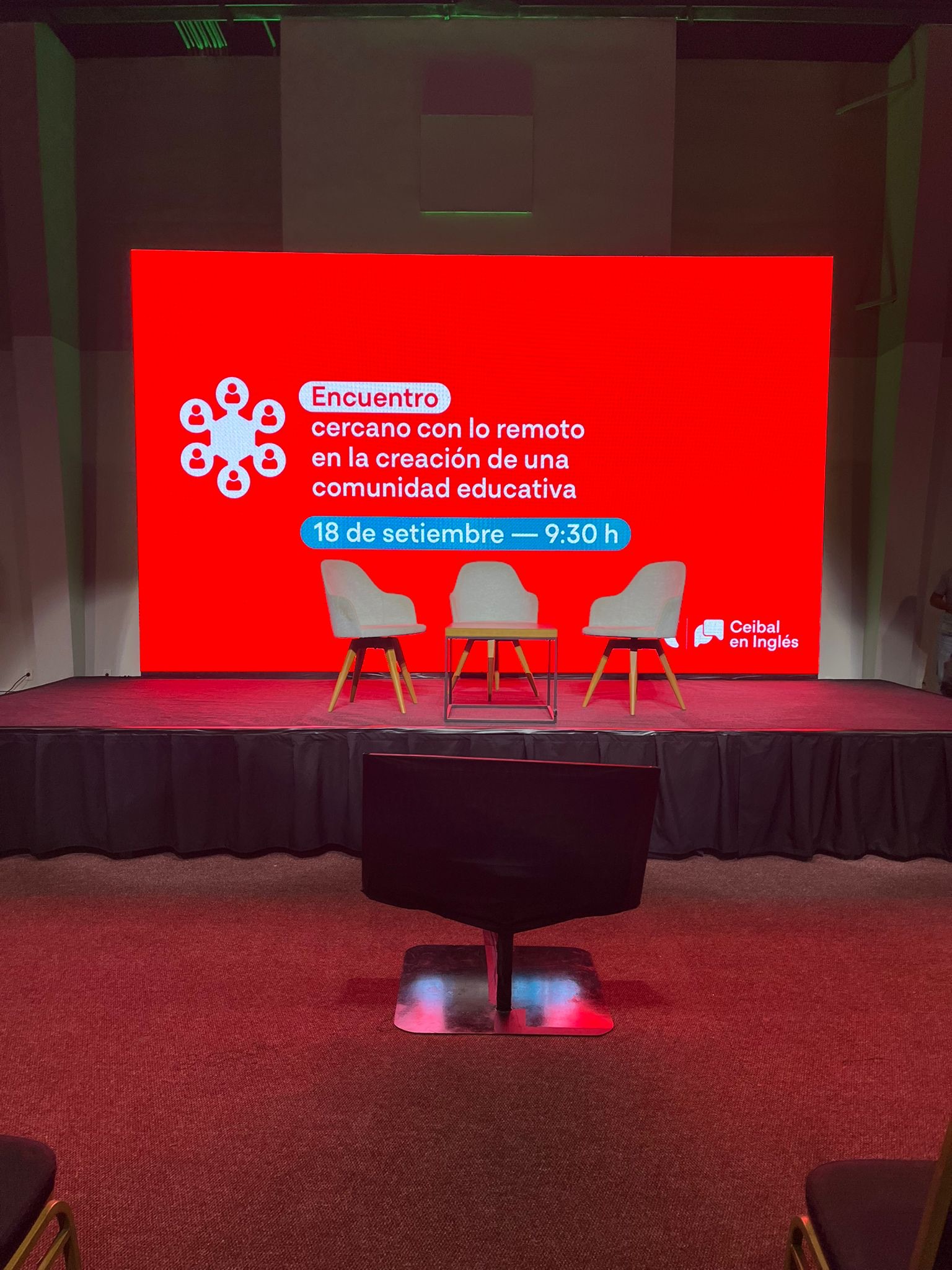 Escenario alfombrado rojo con LED gigante y sillas panelistas