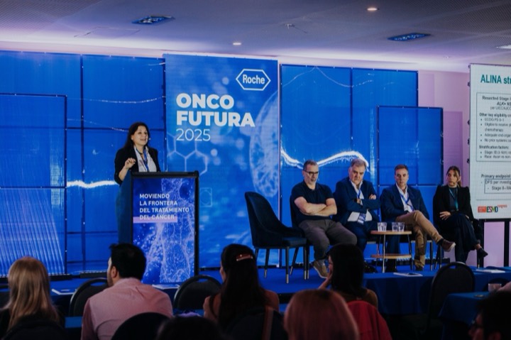 Oradora presentando en podio digital con gráfica Onco Futura de Roche