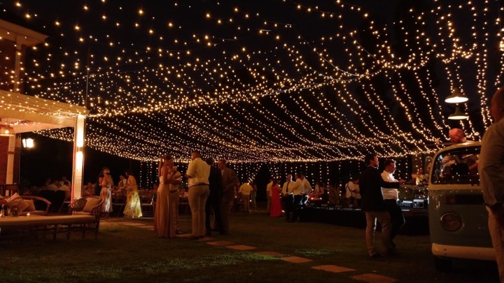 Techo de luces cálidas cubriendo recepción al aire libre, invitados