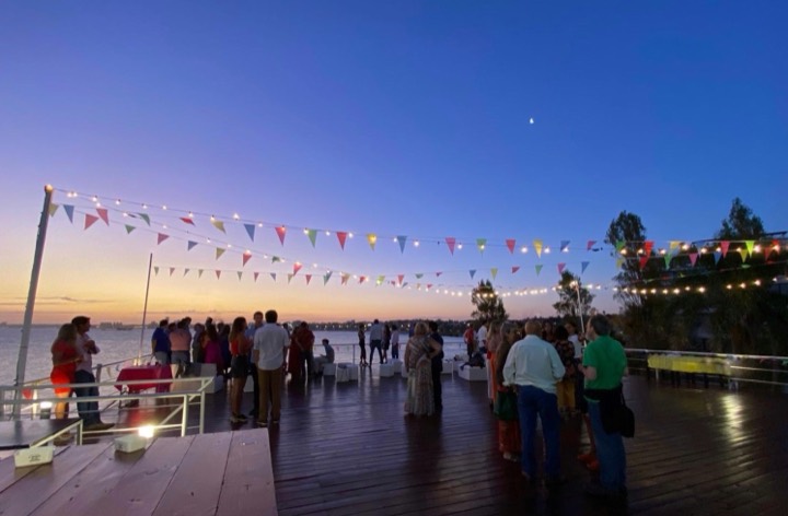 Guirnaldas y banderines sobre terraza junto al agua, atardecer
