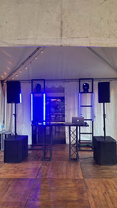 Mesa DJ montada en carpa con parlantes, barras LED y laptop