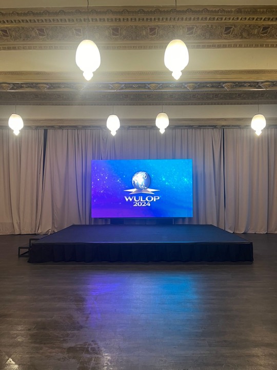 Tarima alfombrada azul con pantalla LED en salón clásico