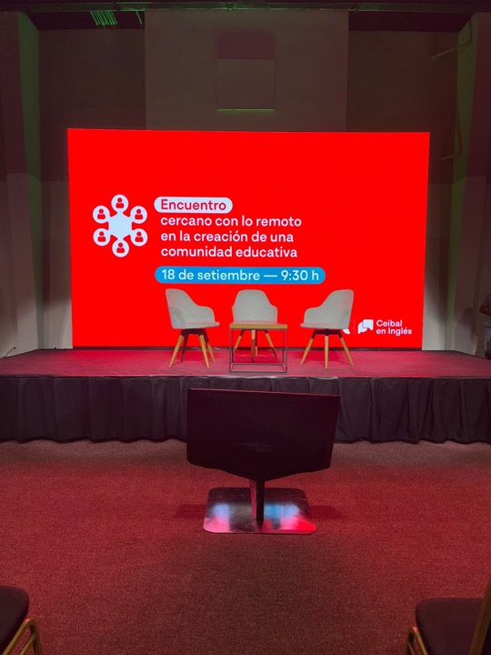 Escenario alfombrado rojo con LED gigante y sillas panelistas