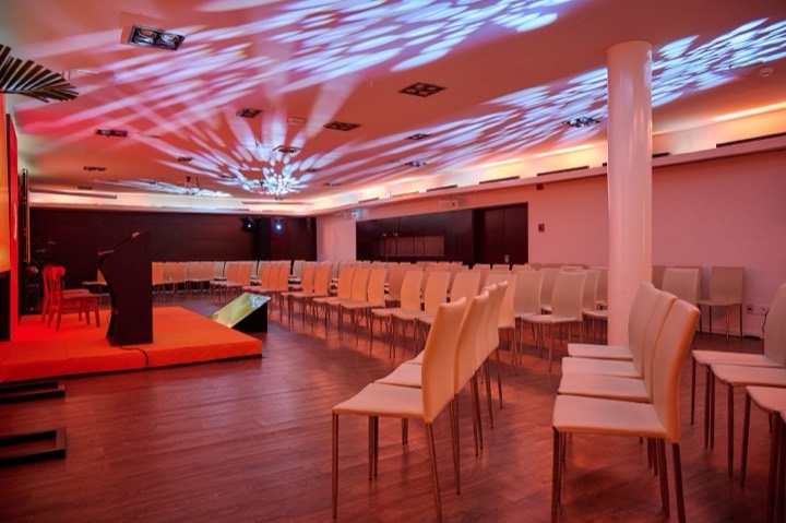 Sala montada con tarima naranja, podio y luces — NH