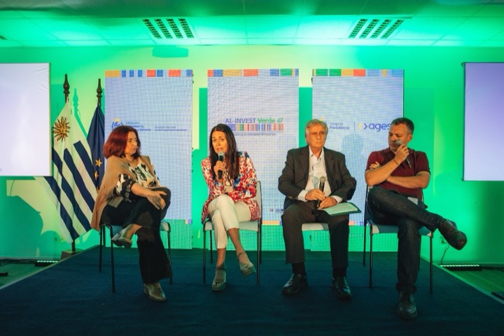 Panel de cuatro sobre tarima alfombrada — AL-INVEST