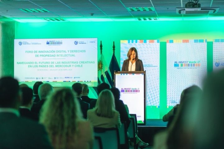 Oradora entre tótems con branding — AL-INVEST Verde